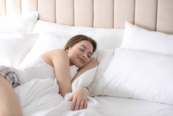 Young woman sleeping on comfortable pillow in bed at home - 写真・画像