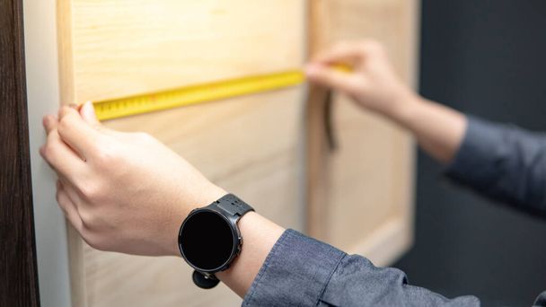 Male hand using tape measure on cabinet panel choosing materials or countertops for built-in furniture design. Shopping furniture and house decoration. Home improvement concept - Photo, Image