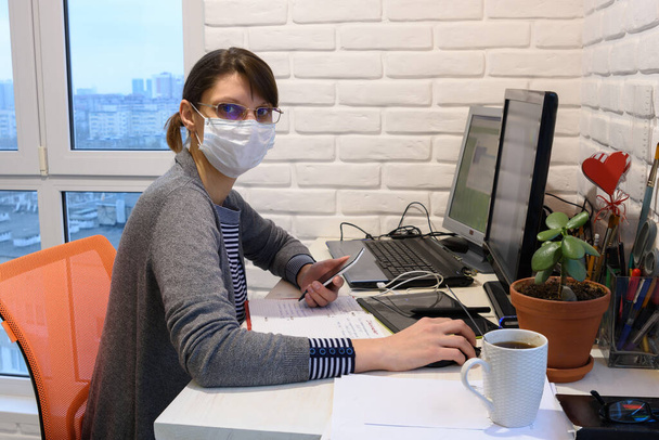 Una chica enferma con una máscara médica en autoaislamiento trabaja remotamente, miró en el marco
 - Foto, Imagen