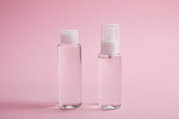 Sanitizador spray e frasco de loção em fundo rosa
 - Foto, Imagem