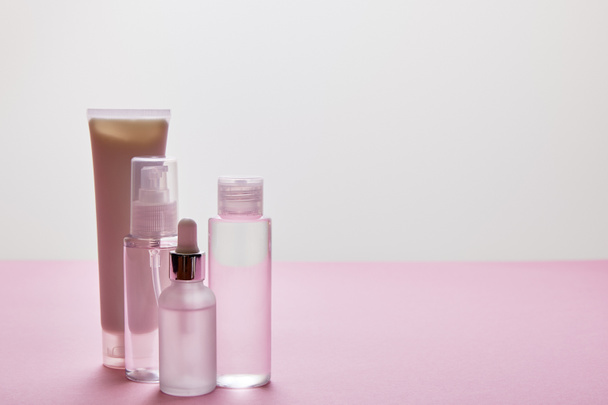 Set di cosmetici per la cura della pelle su sfondo rosa e grigio
 - Foto, immagini