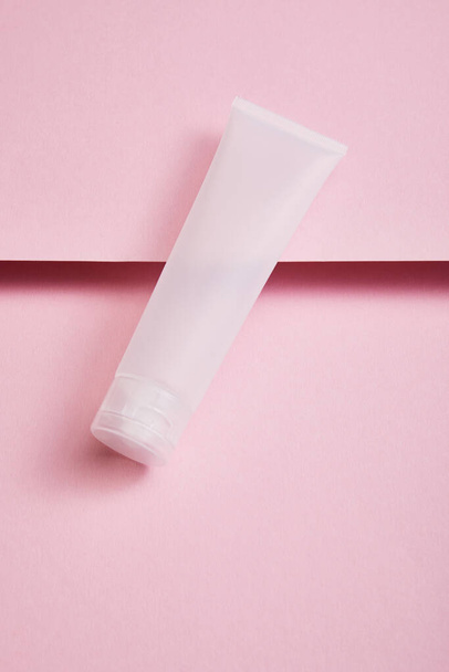 High angle view of empty plastic cosmetic cream tube on pink background - Fotoğraf, Görsel