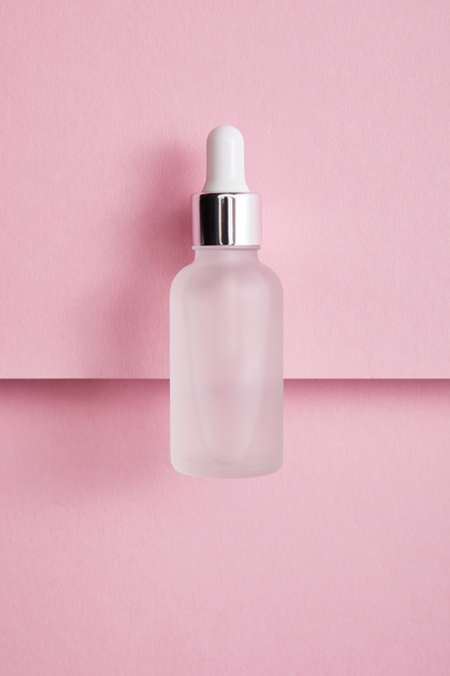 Top view of serum bottle with liquid on pink paper background - Фото, изображение