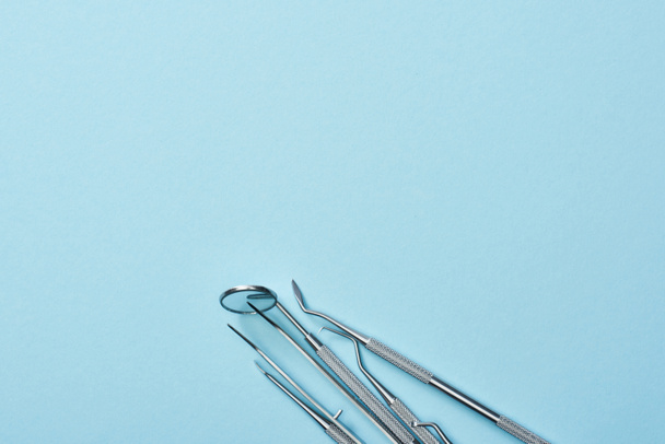 High angle view of metal professional dental instruments on blue background - Foto, afbeelding
