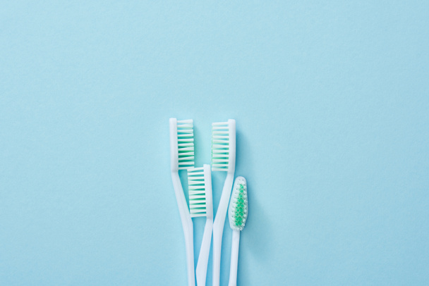 Vista superior de escovas de dentes brancas com cerdas verdes no fundo azul
 - Foto, Imagem