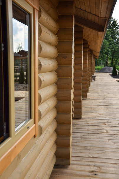 Dřevěná veranda s výhledem na nádvoří se stromy. Krásný domov má omotanou palubu lemovanou dřevěnými madly s výhledem na zahradu. - Fotografie, Obrázek
