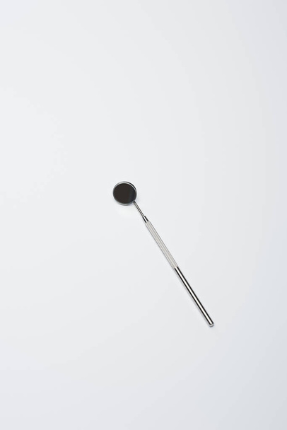 Top view of dental mirror for teeth examination on grey background - Foto, Imagen