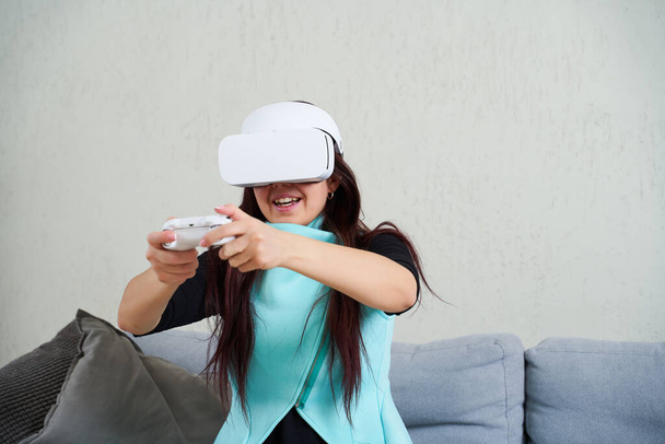 Γυναίκα με ακουστικά εικονικής πραγματικότητας και gamepad παίζει το παιχνίδι. - Φωτογραφία, εικόνα