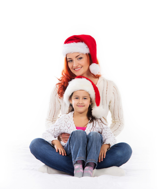 A happy mother and a daughter relaxing in red Christmas hats - Foto, Imagen