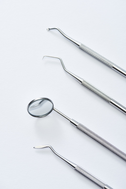 Κάτοψη οργάνων επαγγελματικής οδοντιατρικής εξέτασης με υψηλή γωνία σε γκρι φόντο - Φωτογραφία, εικόνα