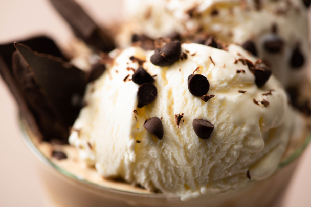 Szelektív fókusz üveg tejshake fagylalttal, darab csokoládé és cukorka bézs  - Fotó, kép