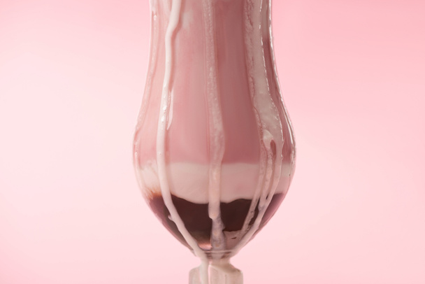 Glass of strawberry milkshake with ice cream dripping on pink background - Photo, Image