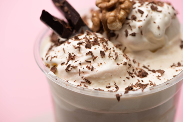 Tek kullanımlık milkshake 'in seçici odak noktası dondurma, ceviz, çikolata parçacıkları ve pembe parçalar.  - Fotoğraf, Görsel