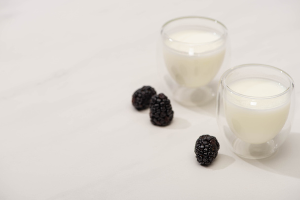 Vista de alto ángulo de vasos de yogur casero con moras sobre fondo blanco
 - Foto, Imagen