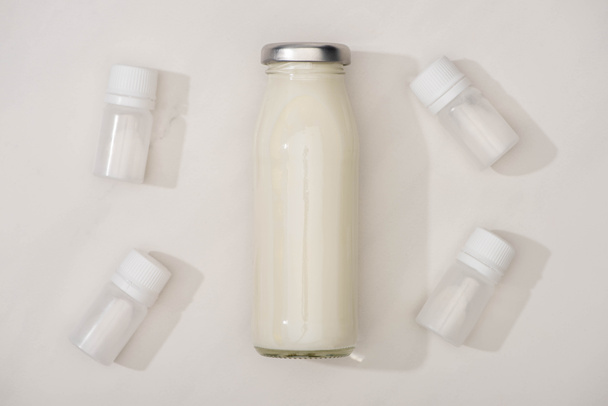 Vista dall'alto di bottiglia di yogurt e contenitori fatti in casa con colture di antipasto su sfondo bianco
 - Foto, immagini