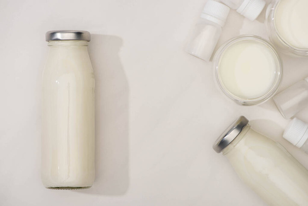 Vista dall'alto di bottiglie e bicchieri di yogurt e contenitori fatti in casa con colture di antipasto su sfondo bianco
 - Foto, immagini