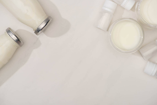 Top view of bottles and glasses of homemade yogurt near containers with starter cultures on white background - Foto, Bild
