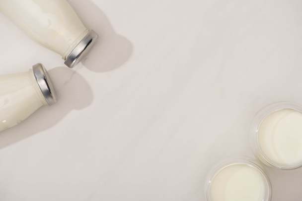 Top view of bottles and glasses of homemade yogurt on white  - Foto, Imagen