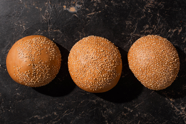top view of fresh baked sesame buns on stone black surface - Photo, Image