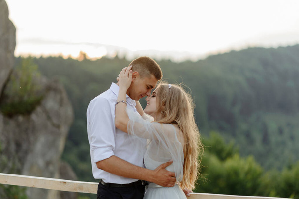 Photoshoot of a couple in love in the mountains. The girl is dressed like a bride in a wedding dress. - Foto, afbeelding