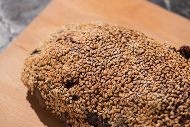 fresh baked black bread with sesame on cutting board - Foto, imagen