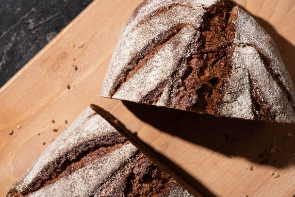 top view of fresh baked cut brown bread on cutting board - Foto, imagen