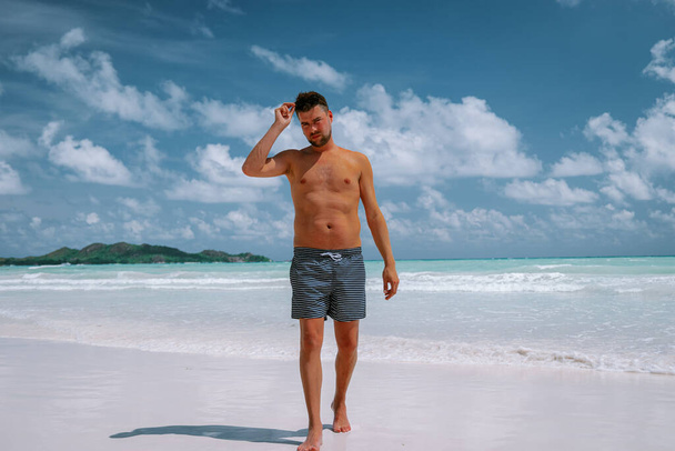 Cote dOr Beach Praslin Seszele, młodzi mężczyźni w średnim wieku w kąpieli krótki spacer po plaży podczas wakacji Secyhelles tropikalna wyspa, biały facet na plaży podczas wakacji Praslin - Zdjęcie, obraz