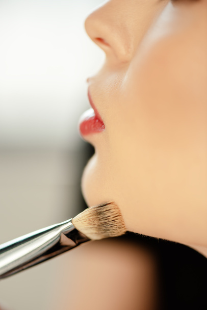 selective focus of cosmetic brush near model with red lips  - Φωτογραφία, εικόνα