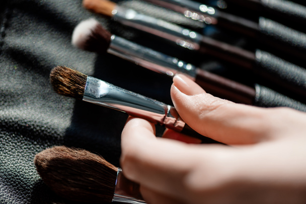 cropped view of makeup artist taking cosmetic brush  - Fotografie, Obrázek