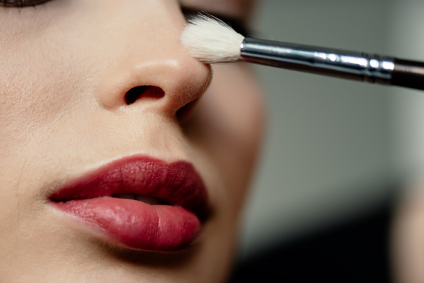 enfoque selectivo de cepillo cosmético cerca de la mujer con labios rojos
  - Foto, Imagen