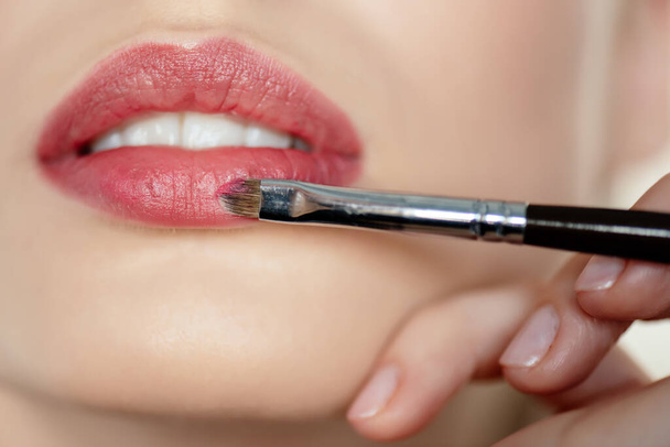 cropped view of makeup artist applying lipstick on girl - Fotó, kép