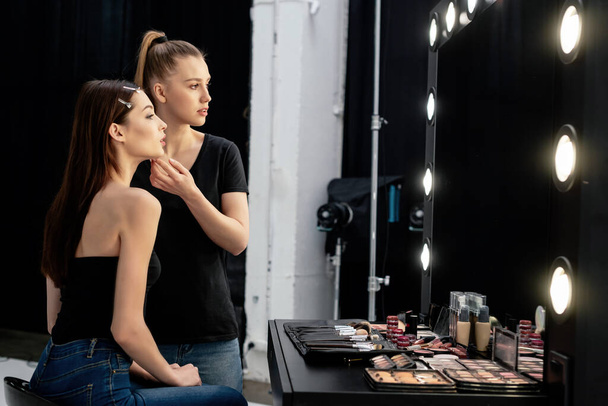 maquillaje artista tocando la cara de modelo atractivo y mirando el espejo
  - Foto, imagen