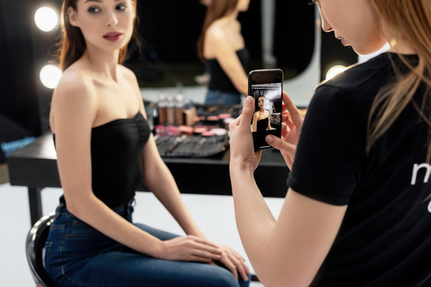 selective focus of makeup artist taking photo of young model  - Fotografie, Obrázek