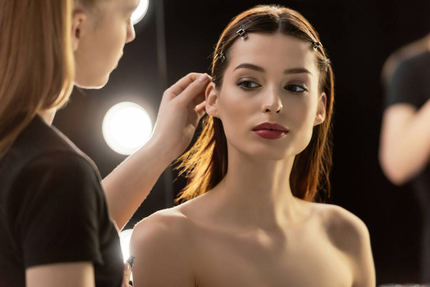 enfoque selectivo de artista de maquillaje tocando el cabello de modelo joven
  - Foto, Imagen