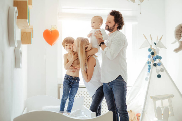 Four family member playing together with two cute boys in a sunny bright room. Enjoying sunny days at home during quarantine. Perfect parenting relationship. Stay home together. Family time - Foto, imagen