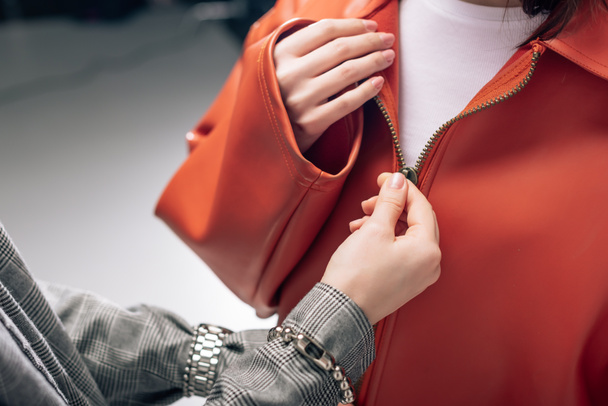 cropped view of stylist fastening zipper on jacket of model  - Фото, изображение
