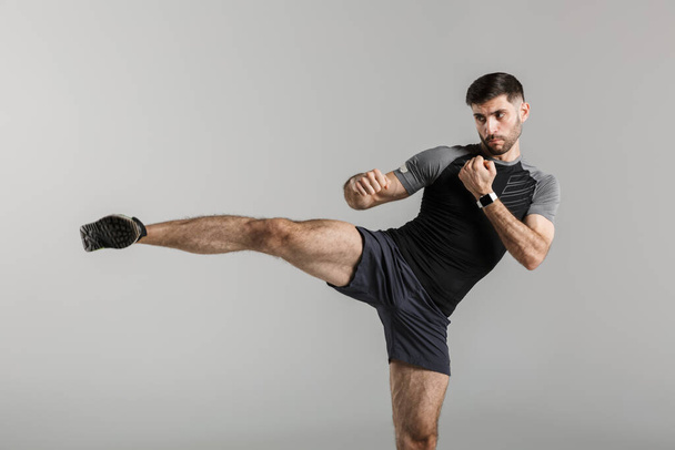 Imagen de un guapo luchador deportivo fuerte aislado sobre fondo de pared gris hacer ejercicios de boxeo
. - Foto, imagen