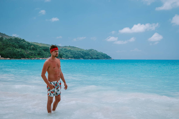 Cote dOr Beach Praslin Seyşeller, tatilde sahilde kısa süre yüzen orta yaşlı adamlar Secyhelles tropikal adasında yürüyen, Praslin tatilinde sahilde olan beyaz adam. - Fotoğraf, Görsel