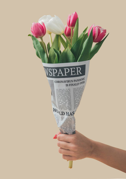 Весняні тюльпани, загорнуті в газети з глобальною пандемією, закінчуються заголовком. Коронавірусна хвороба закінчує пружну концепцію. Підземний фон 19. Ідея квіток.. - Фото, зображення