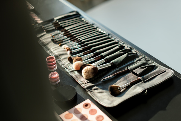 selective focus of makeup brush set near lip balms and eye shadows  - Fotografie, Obrázek