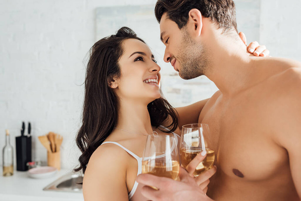 Couple avec des verres de vin étreignant, souriant et se regardant
 - Photo, image