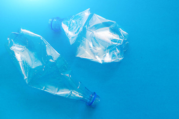 ソリッドブルーの背景にプラスチックボトル。環境を守る。二次原料。ゴミ処理だ。自然を守る。プラスチックの危険性に関する記事。環境に関する記事 - 写真・画像