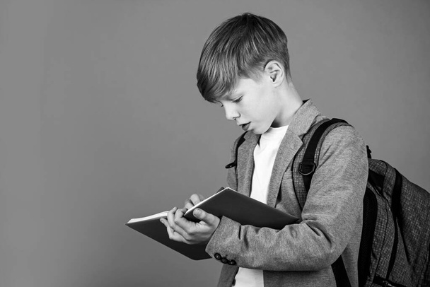 Enriching life with knowledge. Boy student brown background. Small student write in copy-book. Little student do homework assignment. Smart student back to school. Study and learn, copy space - Fotoğraf, Görsel