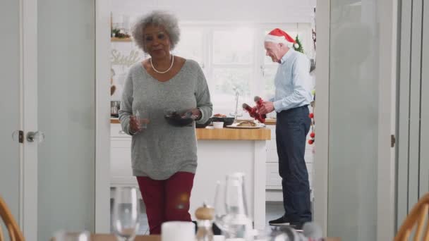 Senior couple at home setting and decorating table for Christmas meal with crackers - shot in slow motion - Metraje, vídeo