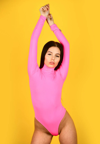 Looking trendy. woman with slim and fit body. girl wear pink bodysuit yellow background. beauty with retro look. skincare and hair stylish concept. summer trend collection. sexy female fashion - Fotoğraf, Görsel