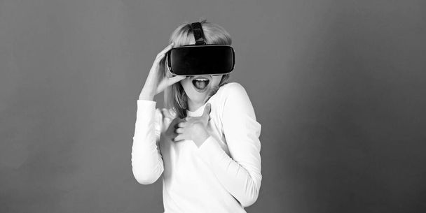 Portrait of young woman wearing VR goggles, experiencing virtual reality using 3d headset. Amazed young woman touching the air during the VR experience. Virtual 3d. - 写真・画像