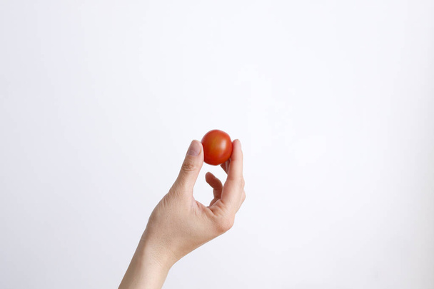 Female hand with cherry tomatoes on a white background in daylight - Fotoğraf, Görsel