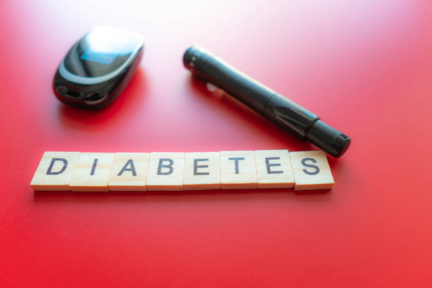 Glükózmérő orvosi sztetoszkóppal, a cukorbetegség koncepciója, egészséges életmód és táplálkozás. Cukorbeteg szöveg. Piros háttér - Fotó, kép