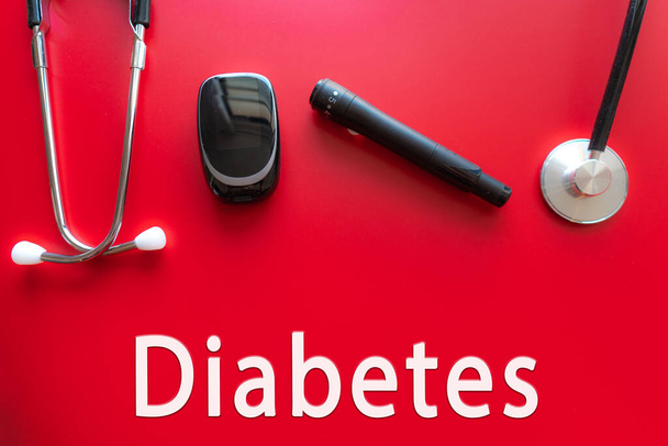 Miernik glukozy ze stetoskopem medycznym, koncepcja cukrzycy, zdrowego trybu życia i odżywiania. Cukrzyca Tekst. Czerwone tło - Zdjęcie, obraz