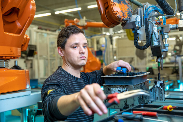 Umbau des Roboters zu einem neuen Produkt. Technisch stellt der Arbeiter die Maschine ein. Konzept Industrie 4.0 - Foto, Bild